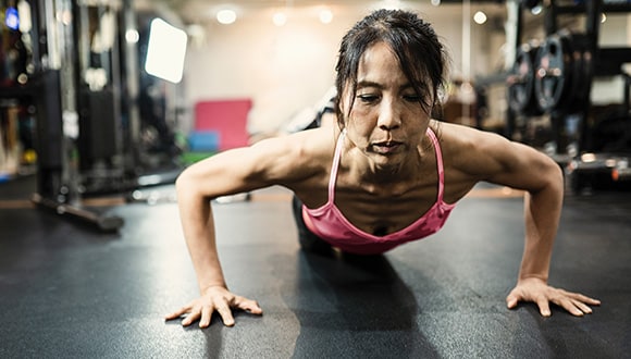 A woman doing resistance training by doing push ups at the gym